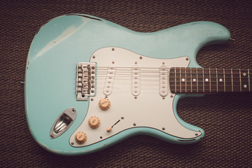 Light blue electric guitar in a purple texture background.