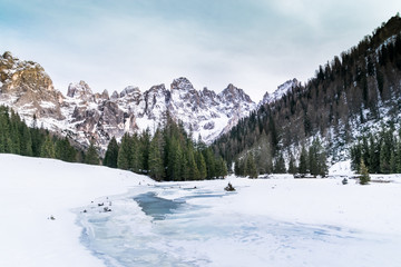 Fototapeta na wymiar Torrente travignolo congelato e panorama con le pale di san martino innevate in Val Venegia. Trentino Alto Adige escursione con le ciaspoole