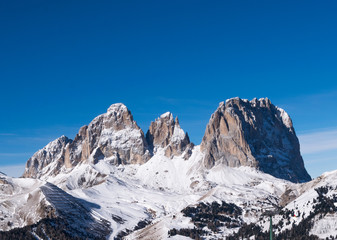Fototapeta na wymiar Sassolungo visto dalle piste da sci della ski area belvedere in Val di Fassa. Una delle stazioni sciistiche più grandi del Trentino Alto Adige e cuore delle Dolomiti invernali