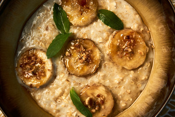 Breakfast oatmeal porridge bowl with banana and caramel, close-up