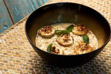 Breakfast oatmeal porridge bowl with banana and caramel, close-up
