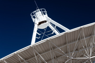 Very Large Array close view of underside of a radio antenna dish VLA against a deep blue sky, space exploration, horizontal aspect