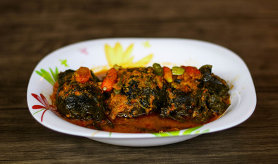 Buntil on wood background. Buntil is a traditional Javanese dish of grated coconut meat mixed with teri (anchovies) and spices, wrapped in papaya, cassava, or taro leaves  then boiled in coconut milk