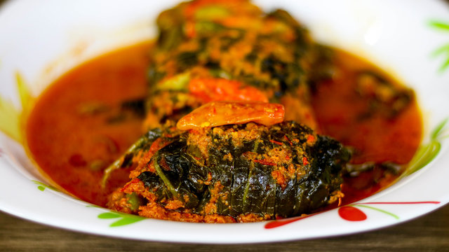 Buntil on wood background. Buntil is a traditional Javanese dish of grated coconut meat mixed with teri (anchovies) and spices, wrapped in papaya, cassava, or taro leaves  then boiled in coconut milk