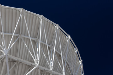 Very Large Array sweeping curve of a radio telescope antenna dish, white against a dark sky, science technology engineering, horizontal aspect