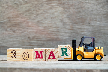 Toy forklift hold block R to complete word 30mar on wood background (Concept for calendar date 30 in month March)
