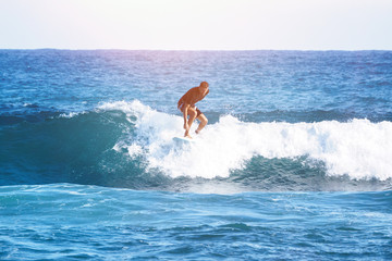 An adult rides a wave on a surfboard. Surfing.