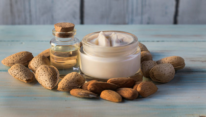 Facial cream and almond oil surrounded by natural almonds