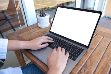 Mockup image of a woman using and typing on laptop with blank white screen , sitting in the outdoors