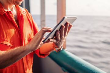 Marine chief officer or captain on deck of vessel or ship watching digital tablet. Internet and home connection at sea.