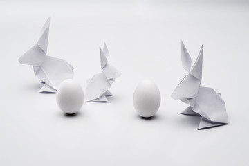 White Easter origami bunnies and eggs on a white background.