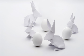 White Easter origami bunnies and eggs on a white background.