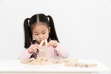 Young little cute asian girl build a house from wooden block construction, wood toy, jenga house on...