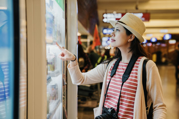 asian travel woman photographer using modern vending machine in airport while waiting for plane...