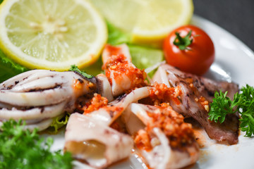 Squid salad with chilli sauce spicy herbs and spices / Grilled squid slice on plate in the seafood restaurant