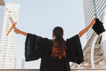 Back side body of happiness young asian woman student in  graduation gown and holding graduation cap with diploma