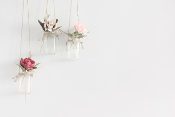 Hanging glass jars with flowers interior wall decoration with copy space for text.