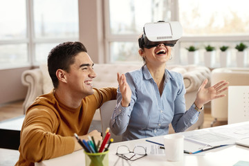Young playful business coworkers having fun with virtual reality simulator.