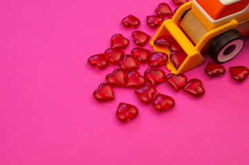 Toy excavator raking hearts. Pink background. Children's love game.