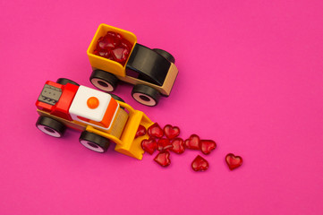 Toy excavator raking hearts. Pink background. Children's love game.