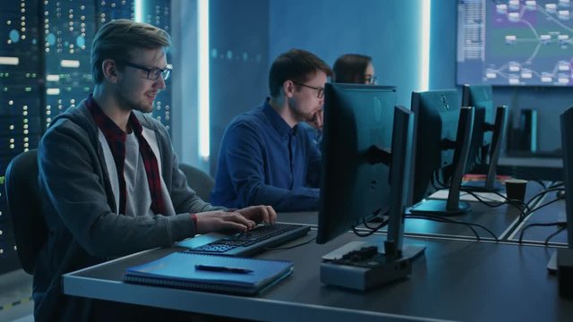 Team of Young IT Programers Working on Desktop Computers in Data Center System Control Room. Displays Show Concept: Software Development / Code Writing / Database Architecture. Technical Department