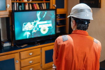 Marine chief officer wearing coverall and helmet on a ship or vessel having fun watching TV. Recreation during at sea