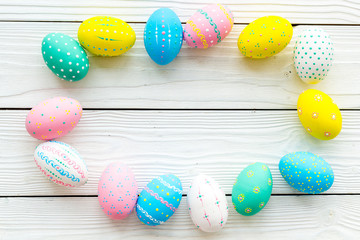 Colorful Easter eggs frame on white wooden background top view space for text