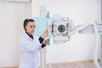  lateral view of a woman radiologist adjusting the X-ray machine in examination rom