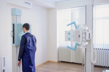lateral view of a female radiologist doing the paranasal sinuses X-ray to a male patient in examination room