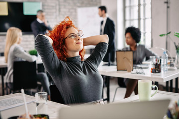 Satisfied businesswoman day dreaming while relaxing in the office.
