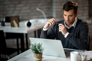 Concentrated businessman reading something on a computer while working in the office.