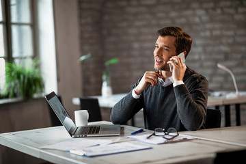 Happy businessman making a phone call on mobile phone while working in the office.
