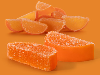 Two marmalade orange slices and a pile of slices on a colored background