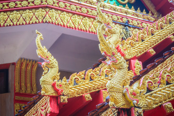 Fototapeta na wymiar Beautiful golden naga sculptures on the church gable roof at the public Buddhist temple in Thailand.