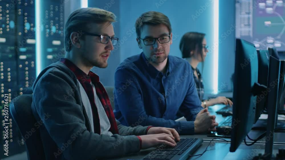 Poster Two Professional IT Programers Discussing Technical Data Show on Desktop Computer Display. Working Data Center Technical Department with Server Racks in the Background
