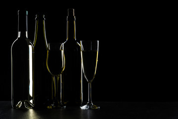 Bottles of wine and different glasses of wine on a dark background