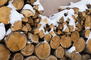 Chopped stock of firewood under snow on the street. Firewood for fireplace and bbq