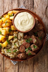 Swedish recipe pyttipanna for beef rydberg with stewed onions and fried potatoes with mustard sauce close-up on a plate. Vertical top view