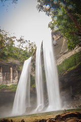 Naklejka premium Huai Luang Waterfall, also known as Namtok Huai Luang or Namtok Bak Teo. The waterfall is plunging down three steps from an elevation of 30 meters with pool, white beach and turquoise colored water.