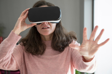 Scared woman in VR goggles playing video game