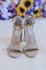 White jeweled Brides Shoes in front of yellow sunflower and purple flowers bouquet