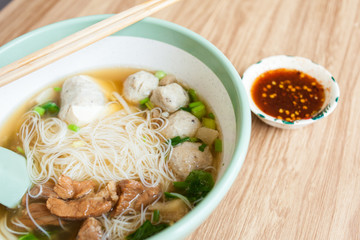 noodle with soup in the big bowl pork and meatball with chilli sauce on the wood table 