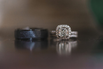 Silver and black wedding rings with diamonds on  reflective surface