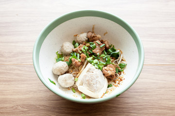 Dry noodle with pork meatball, pork boil and tofu with pork on white bowl on the wood table 