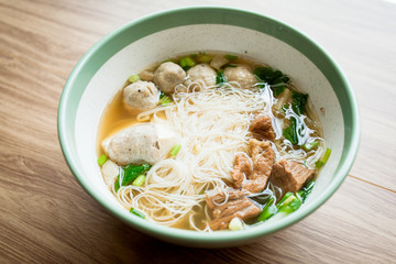Soup and noodle with pork meatball and boil pork with vegetable serve with big bowl on the wood table 