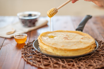 A stack of homemade pancakes on a frying pan, brown background
