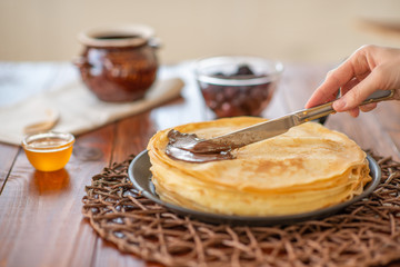 A stack of homemade pancakes on a frying pan, brown background