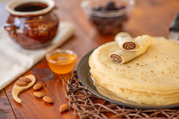 A stack of homemade pancakes on a frying pan, brown background