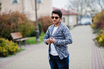 Stylish indian young man at sunglasses wear casual posed outdoor.