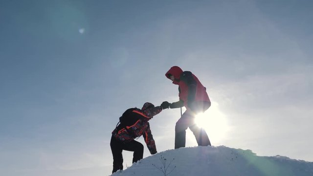 Tourists teamwork, climbing the mountain, helping each other, reaching the top. Overcoming difficulties, helping hand.